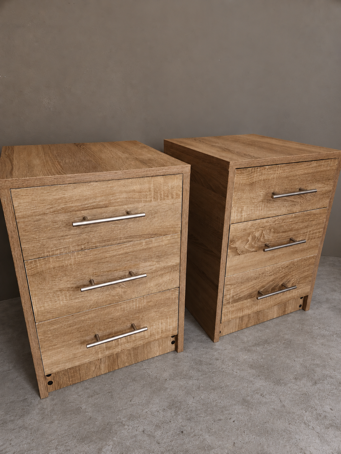Deux meubles assortis en finition bois, avec trois tiroirs chacun, sur un sol gris devant un mur uni