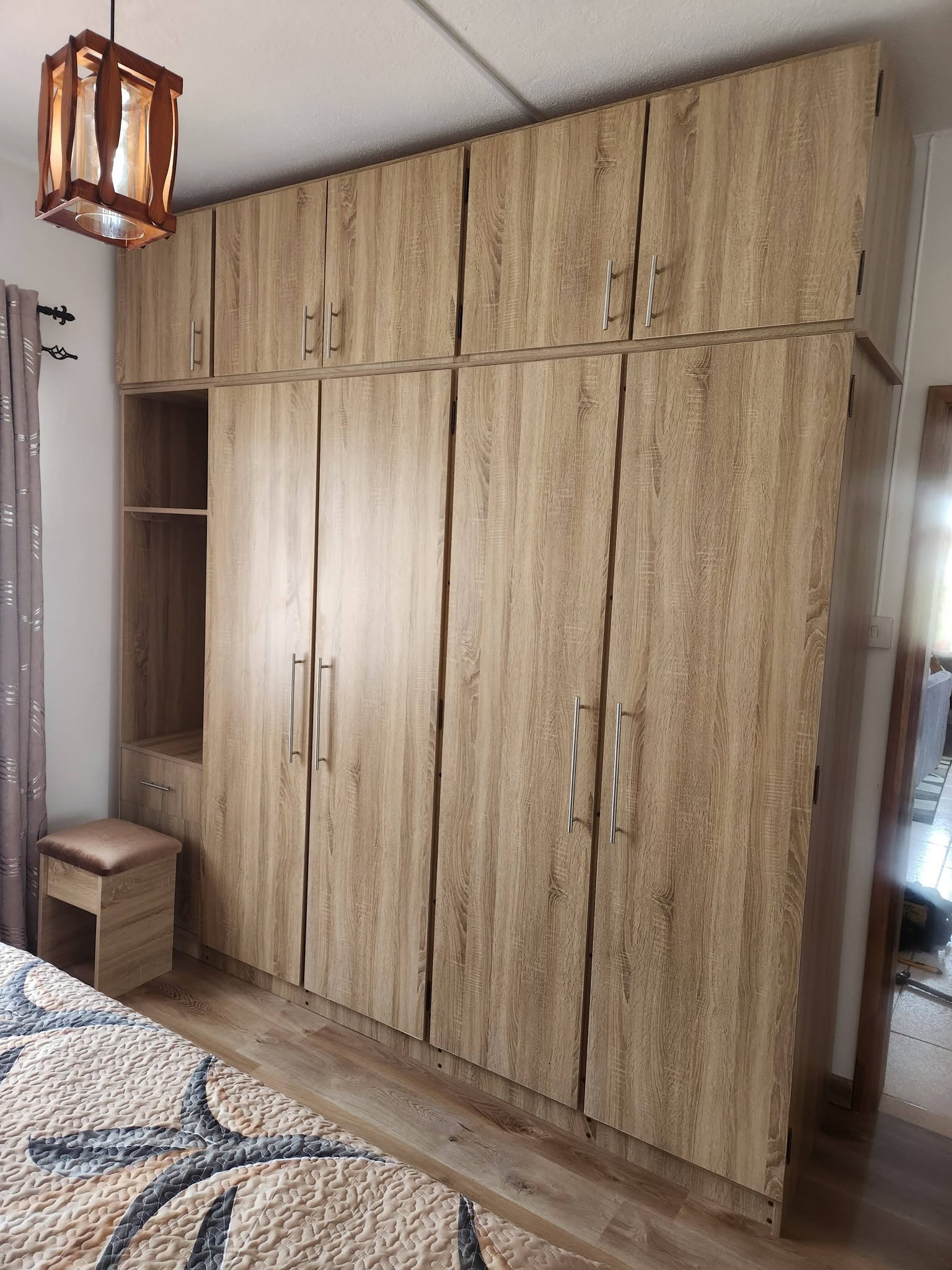 Armoires de chambre intégrées en bois clair, avec placards hauts, niche ouverte et poignées argentées
