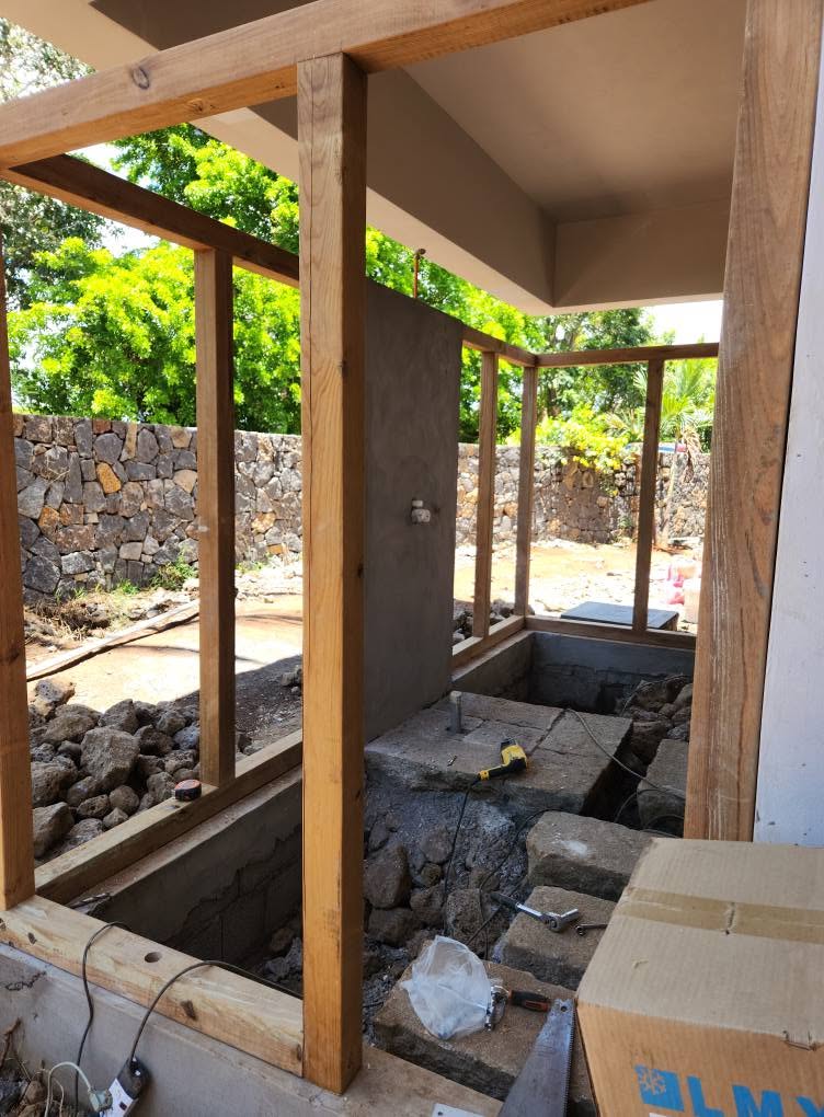 Montants et traverses en bois en cours de pose devant une maison et un jardin